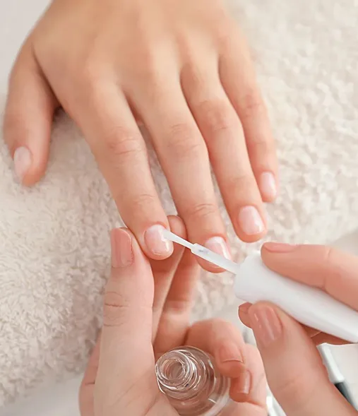 Technician applying gel polish to a client's nails, clear polish bottle in frame