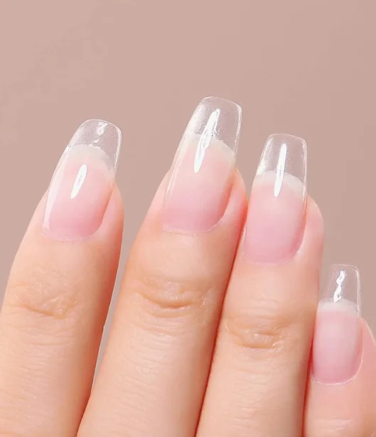 Close-up clear French-style nails across four fingers on a nude backdrop